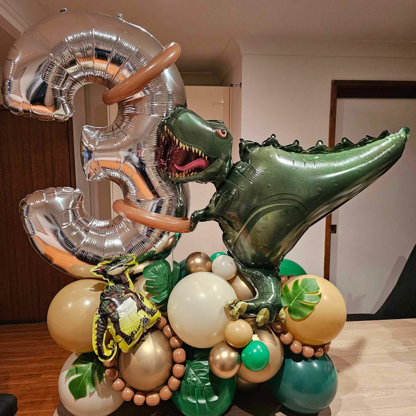 Dinosaur balloon decoration. Balloon Marquee with Jumbo Number balloon, dinosaur foil balloon and faux leaves added.