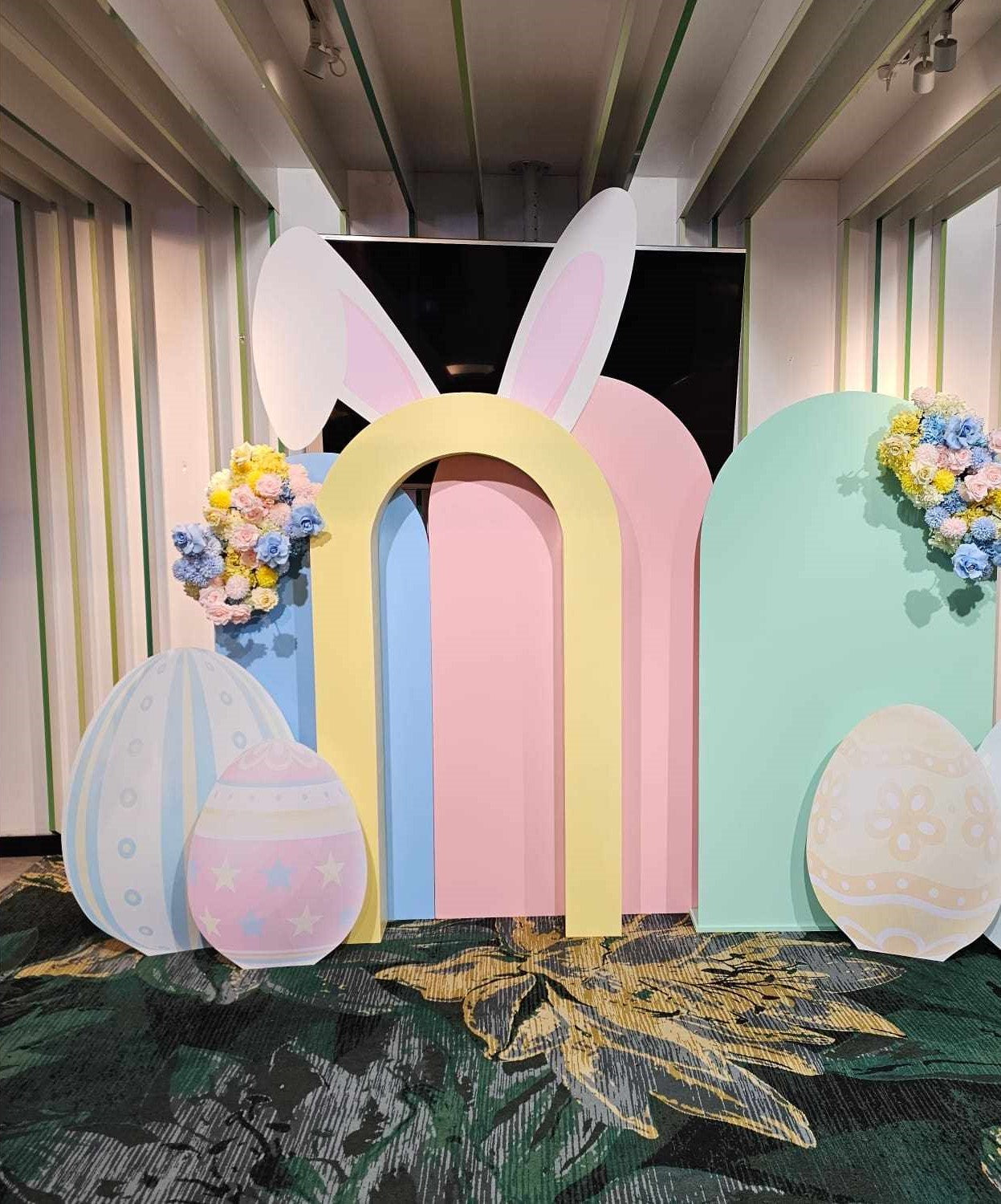 Open Arch backdrop in this Corporate Easter display, featuring Easter egg cutouts, faux floral arrangements in pastel colours and pastel arch backdrops