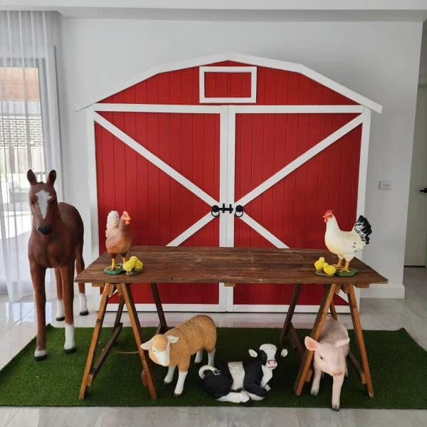 Red Barn door farm yard backdrop. Wooden trestle table and farm animal props for farm themed birthday party decorations. lamb, Calf, piglet, foal chickens and chicks lifesize props 