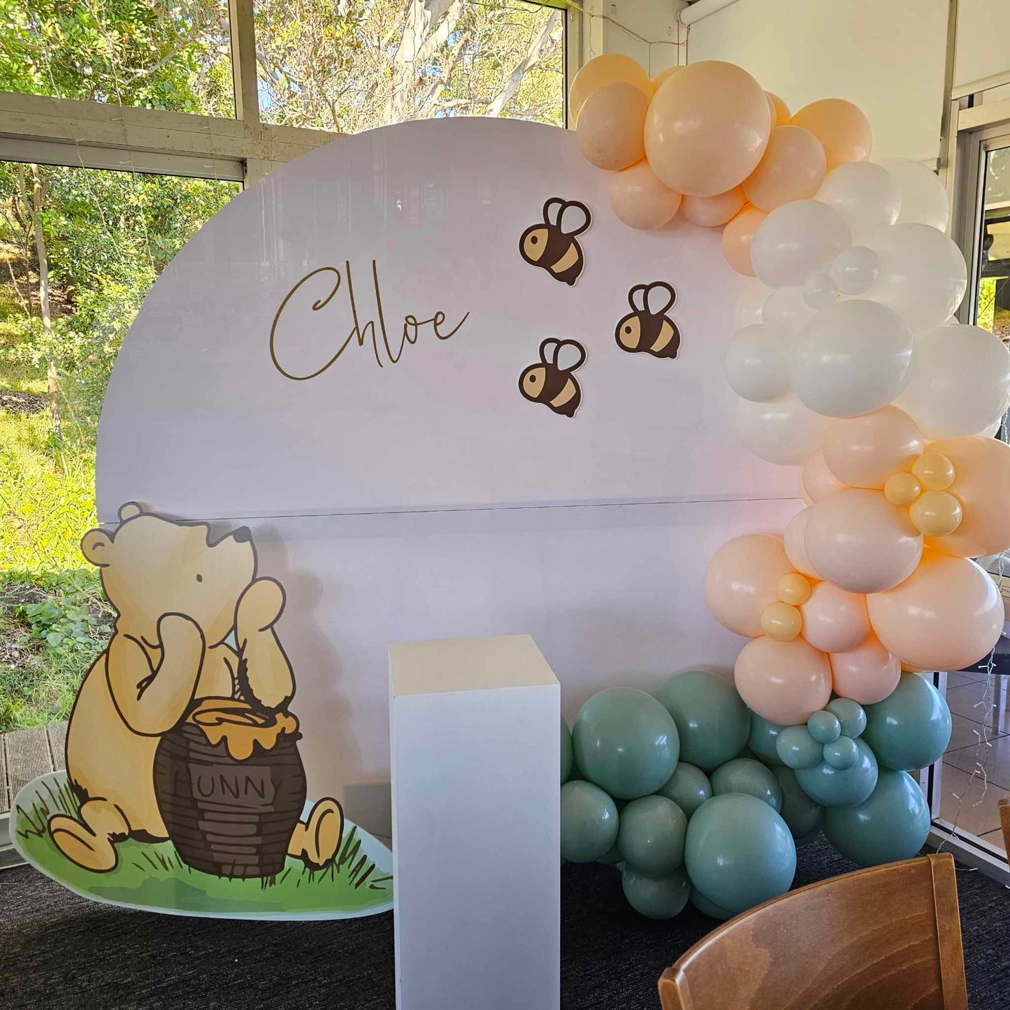 Winnie the pooh cutout with bumble bees for baby shower, baby sprinkle or birthday decorations. Pictured with our square cake plinth in white and organic balloon arch on our white round wall