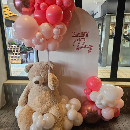 Lifesize teddy bear hire, with white arch backdrop and balloon garland for a Beary cute baby shower decoration