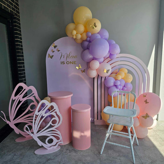 White Vitnage high chair coupled with our Rainbow arch, medium arch backdrop, butterfly props and Ripple plinths. Balloon garland and paper butterflies added.