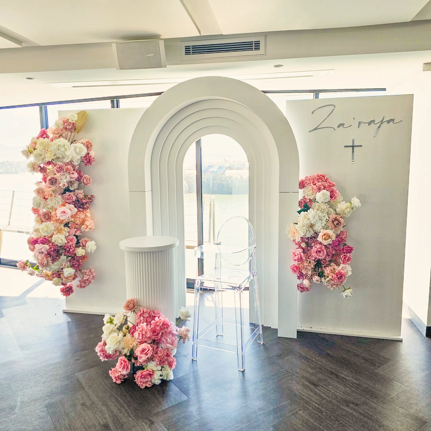 Our stepped arch perfect for baptism  or christening with faux floral arrangements, large white ripple plinth and personalisation.