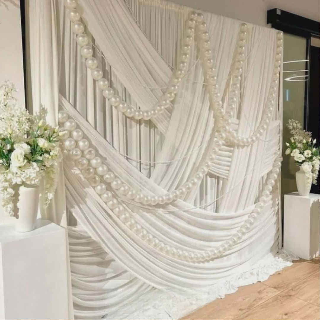White draped fabric with pearl decorations and floral arrangements for a bridal shower